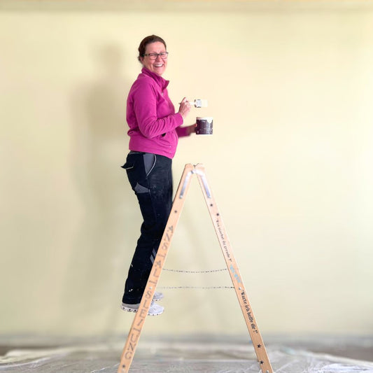 Frau streicht eine Wand mit Kreidefarbe