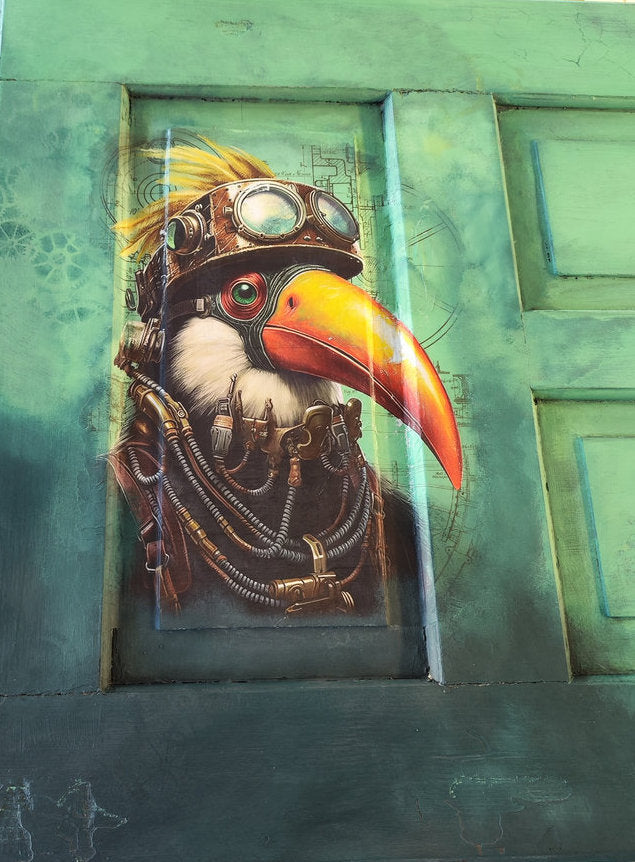 Ausschnitt einer grün gestrichenen Tür mit Decoupage Papier Toucan