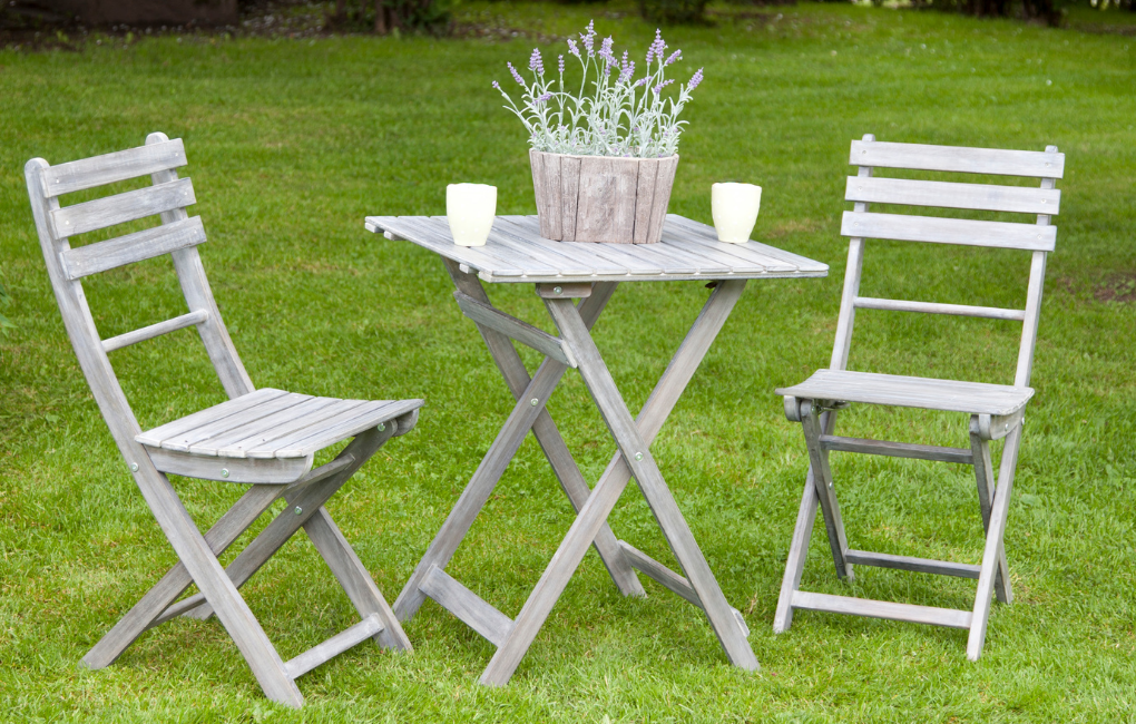 Ein Tisch mit 2 Stühlen aus Holz in einem Garten